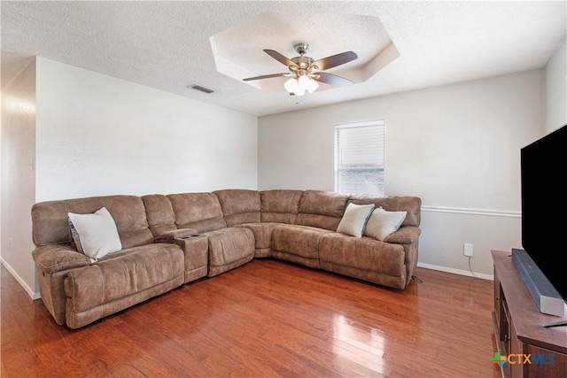 living area featuring wood finished floors, visible vents, a textured ceiling, and a ceiling fan