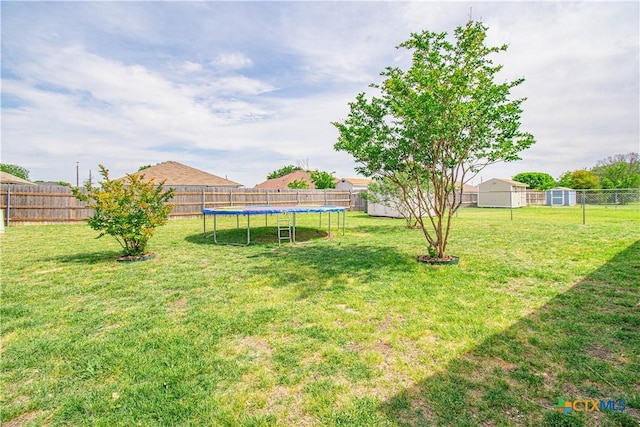 view of yard with a fenced backyard, an outbuilding, a shed, and a trampoline
