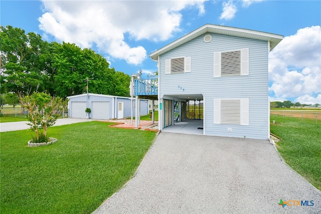 view of front facade featuring a garage, a carport, a front lawn, and an outdoor structure