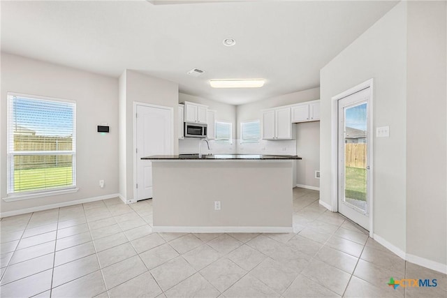 1041 Lakeway Crossing Dr, Temple, TX 76502 - kitchen featuring stainless steel microwave, white cabinetry, light tile patterned floors, and plenty of natural light
