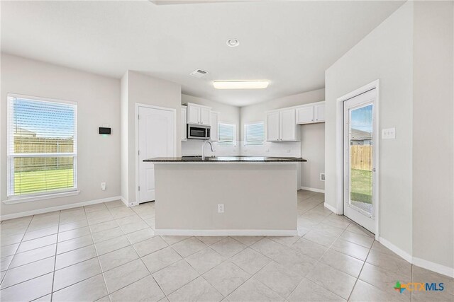 1041 Lakeway Crossing Dr, Temple, TX 76502 - kitchen featuring stainless steel microwave, white cabinetry, light tile patterned floors, and plenty of natural light
