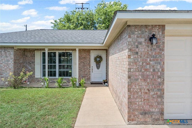 605 Aikman Dr, Troy, TX 76579 - property entrance featuring brick siding, an attached garage, roof with shingles, and a lawn