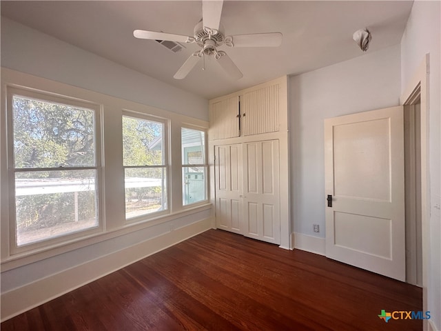 unfurnished bedroom featuring ceiling fan, dark hardwood / wood-style floors, and a closet