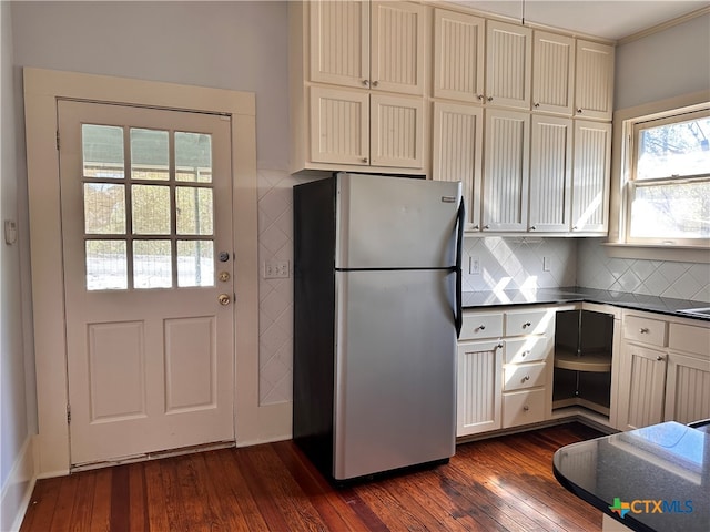 kitchen with stainless steel fridge, dark hardwood / wood-style floors, plenty of natural light, and tasteful backsplash