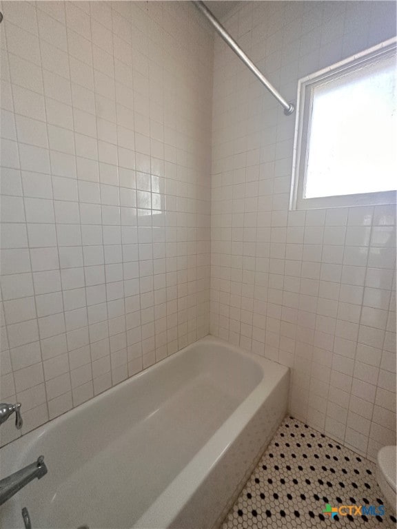 bathroom with toilet and tiled shower / bath combo