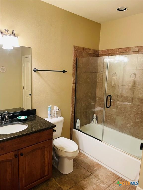 full bathroom featuring vanity, tile patterned flooring, enclosed tub / shower combo, and toilet