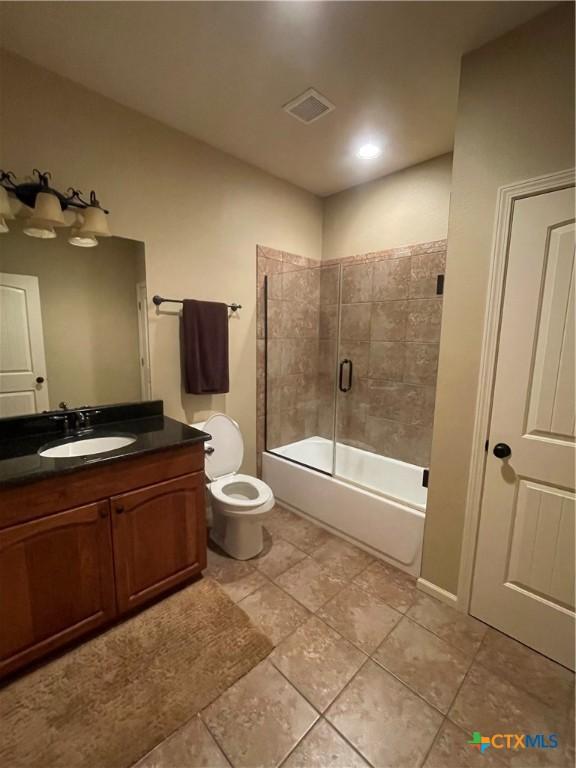 bathroom with shower / bath combination with glass door, tile patterned flooring, visible vents, toilet, and vanity