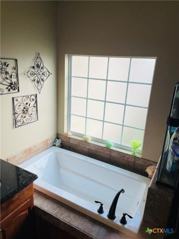 bathroom featuring vanity and tiled bath