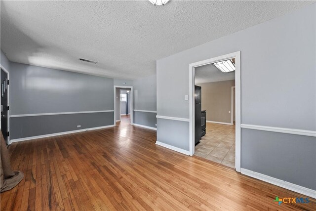 1404 N Beal St, Belton, TX 76513 - spare room featuring wood finished floors, a textured ceiling, and baseboards