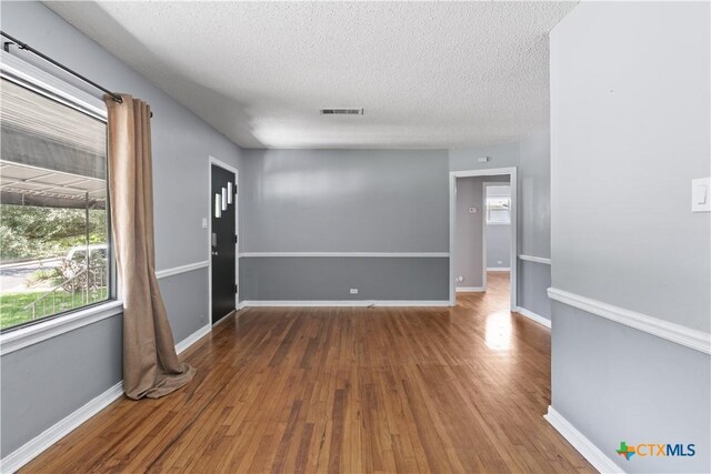 1404 N Beal St, Belton, TX 76513 - spare room with wood finished floors, plenty of natural light, a textured ceiling, and baseboards