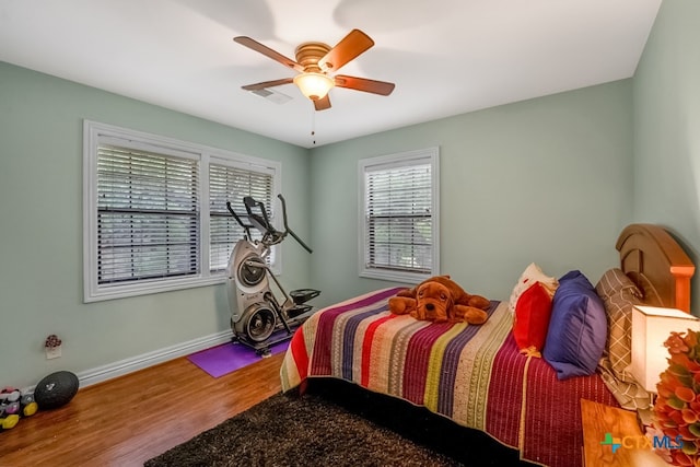 bedroom featuring baseboards, visible vents, wood finished floors, and ceiling fan