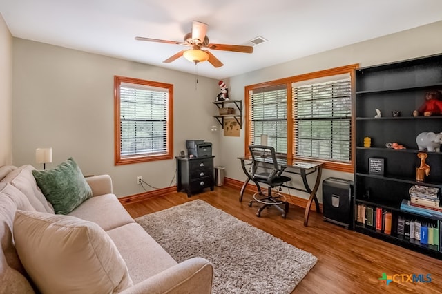 office with wood finished floors, visible vents, a ceiling fan, and baseboards