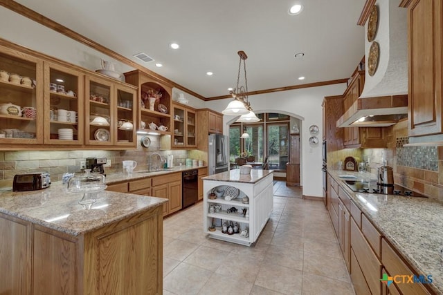 kitchen with hanging light fixtures, light stone countertops, a kitchen island, and black appliances