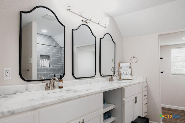 bathroom featuring vaulted ceiling, double vanity, wood finished floors, and a sink