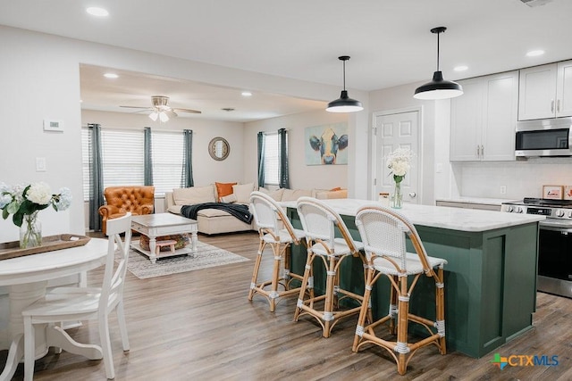 kitchen featuring light stone counters, stainless steel appliances, hanging light fixtures, white cabinetry, and a kitchen island