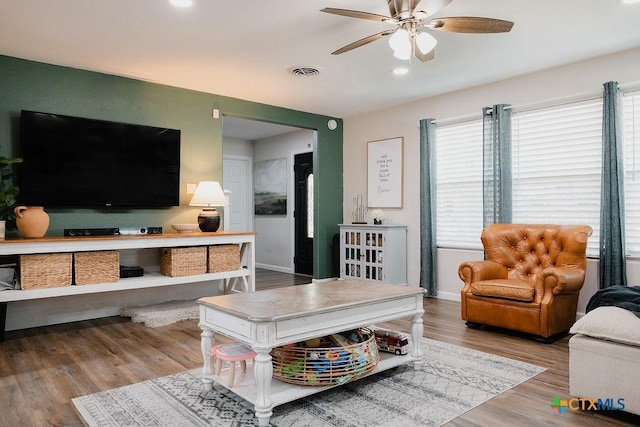 living room featuring a ceiling fan, a healthy amount of sunlight, visible vents, and light wood-style flooring