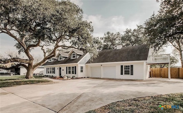 cape cod-style house with driveway, an attached garage, and fence