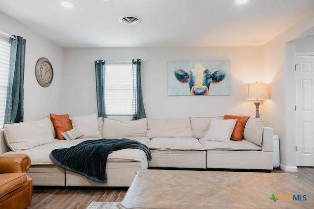 living room featuring baseboards, visible vents, wood finished floors, and recessed lighting