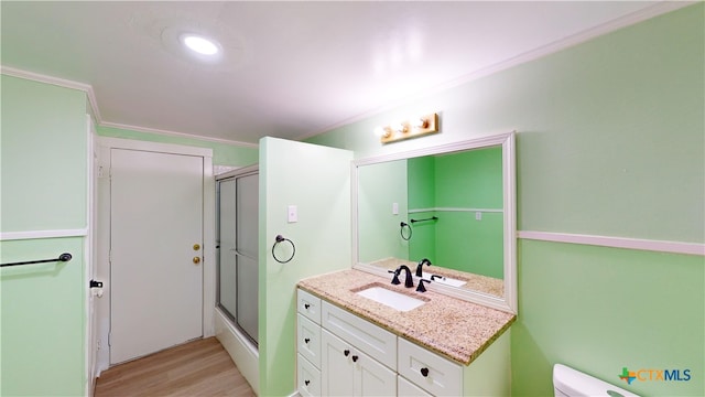 bathroom featuring hardwood / wood-style flooring, ornamental molding, vanity, an enclosed shower, and toilet