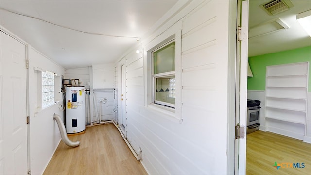 hallway with water heater, light hardwood / wood-style flooring, and vaulted ceiling