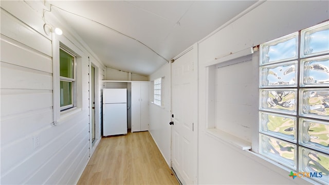 corridor with light hardwood / wood-style floors and lofted ceiling