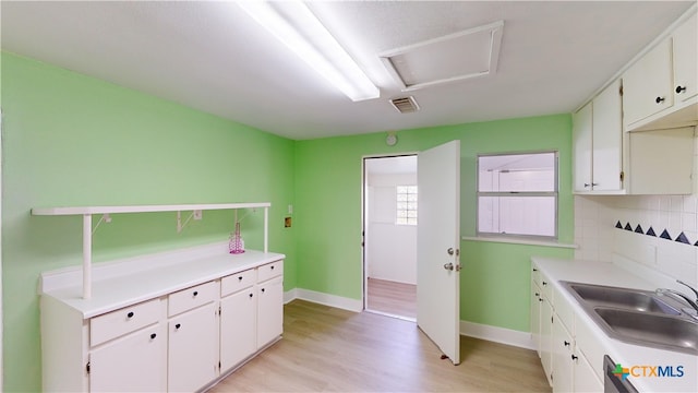 kitchen featuring white cabinets, light hardwood / wood-style flooring, sink, and backsplash