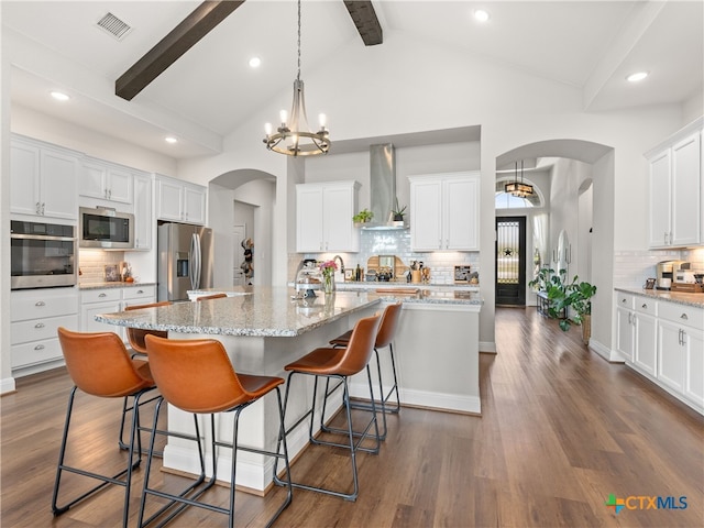 4508 River Rock Rd, Marion, TX 78124 - kitchen with wall chimney range hood, appliances with stainless steel finishes, arched walkways, tasteful backsplash, and beam ceiling