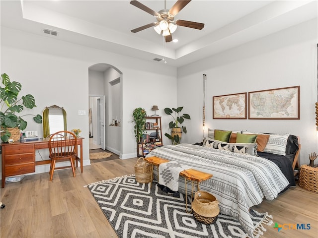 4508 River Rock Rd, Marion, TX 78124 - bedroom featuring arched walkways, a raised ceiling, light wood-style floors, recessed lighting, and baseboards