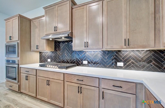 kitchen with appliances with stainless steel finishes, backsplash, light hardwood / wood-style flooring, and light brown cabinets