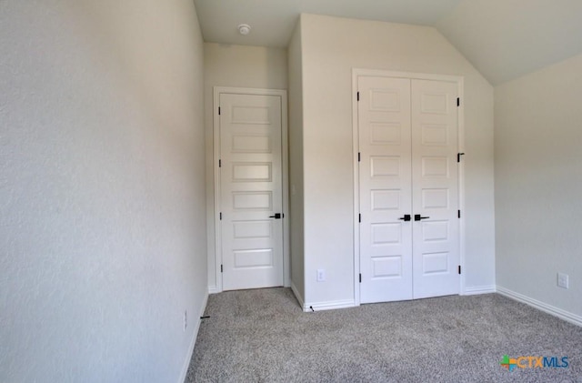 unfurnished bedroom with light carpet, a closet, and lofted ceiling