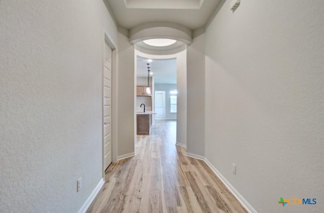 hallway featuring light wood-type flooring, built in features, and sink