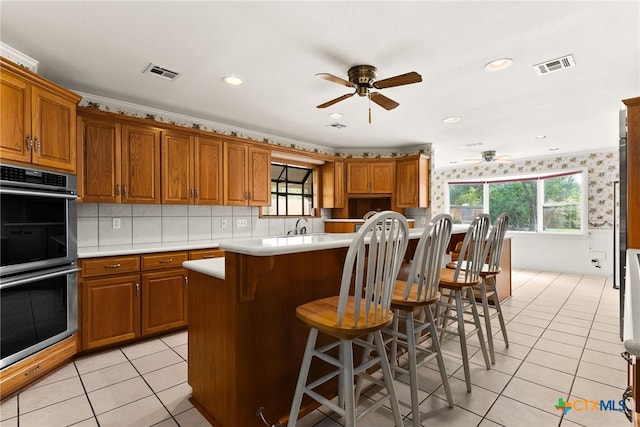 kitchen with plenty of natural light, a kitchen island, a kitchen breakfast bar, and stainless steel double oven