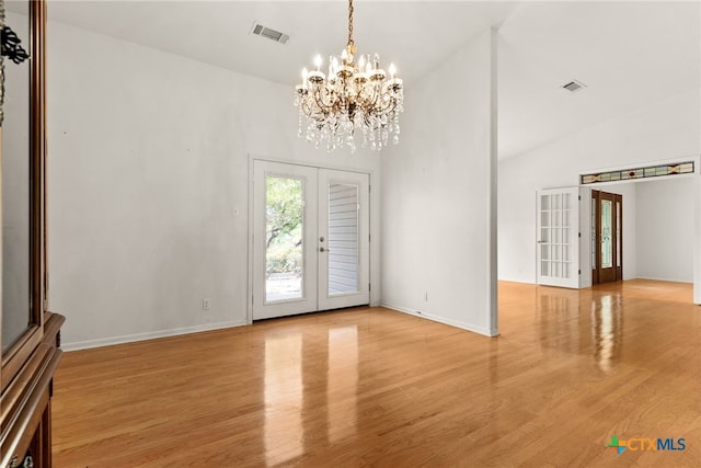 unfurnished room with a chandelier, french doors, light hardwood / wood-style floors, and high vaulted ceiling