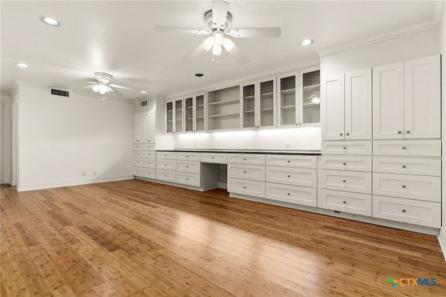 interior space featuring crown molding, ceiling fan, built in desk, and light wood-type flooring