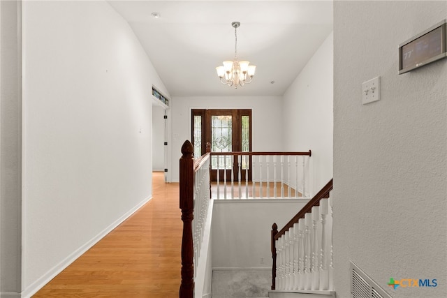 hallway with light wood-type flooring and a chandelier