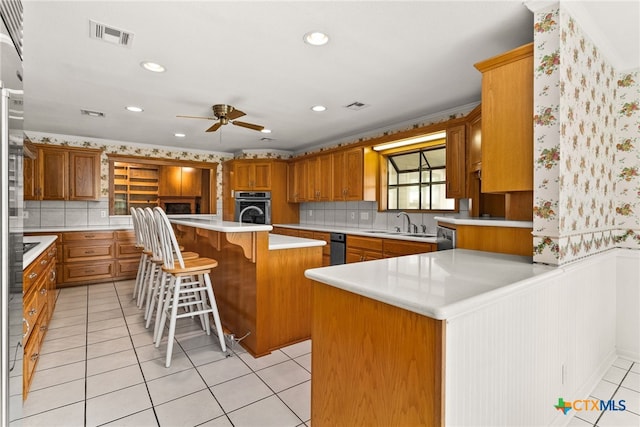 kitchen with ceiling fan, a kitchen breakfast bar, kitchen peninsula, oven, and a kitchen island