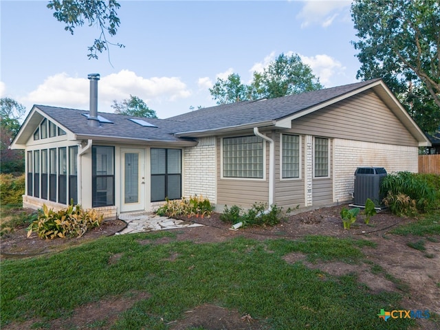 view of front of house with central AC and a sunroom