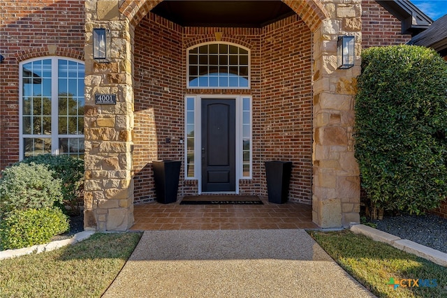 entrance to property featuring stone siding and brick siding