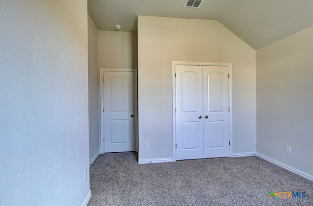 unfurnished bedroom with a closet, vaulted ceiling, and light colored carpet