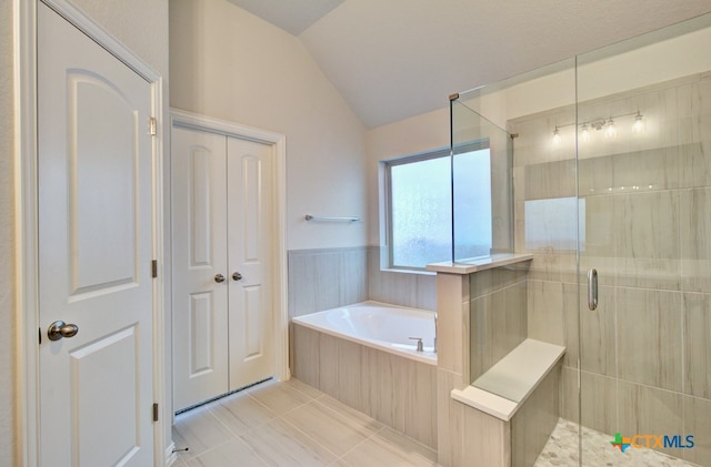 bathroom featuring independent shower and bath, vaulted ceiling, and tile patterned floors