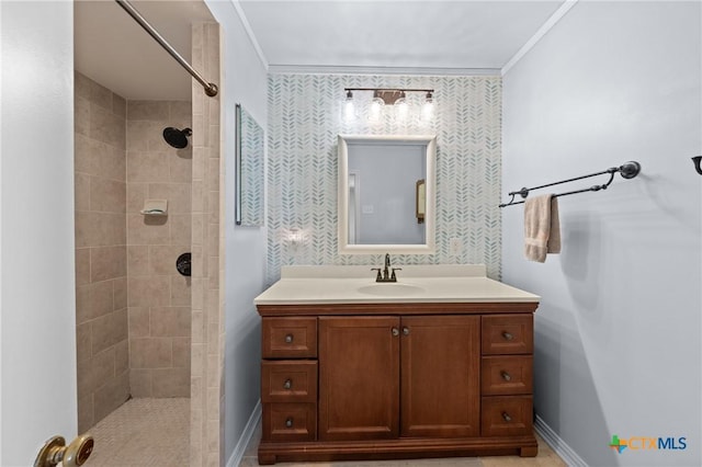 full bath featuring baseboards, tiled shower, vanity, and crown molding