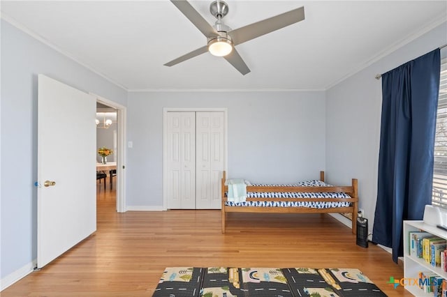 bedroom featuring crown molding, a closet, wood finished floors, baseboards, and ceiling fan with notable chandelier