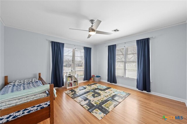 bedroom featuring visible vents, wood finished floors, and ornamental molding