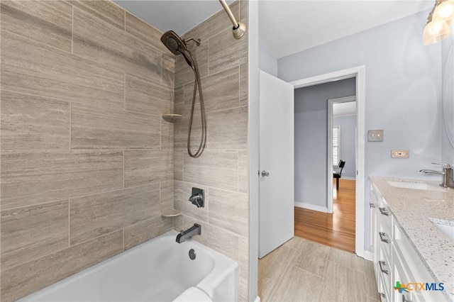 bathroom featuring shower / washtub combination, a sink, baseboards, and double vanity