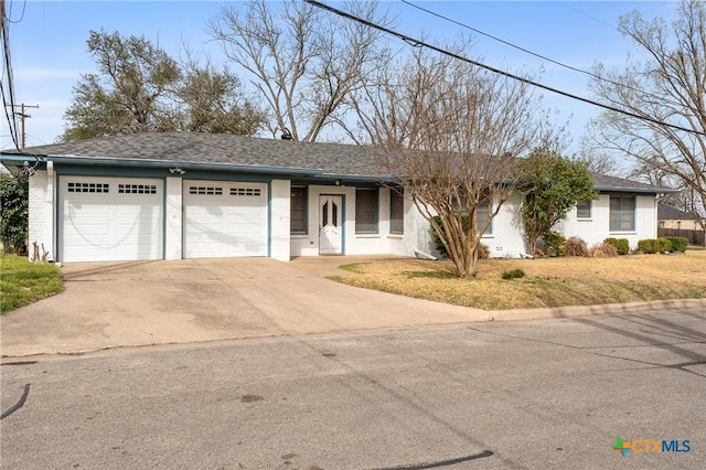 single story home with concrete driveway, a front lawn, roof with shingles, and an attached garage