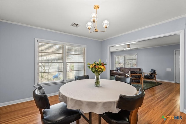 dining space featuring light wood-style floors, visible vents, crown molding, and baseboards