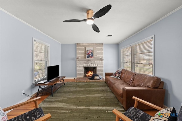 living room featuring a wealth of natural light, a fireplace, crown molding, and wood finished floors