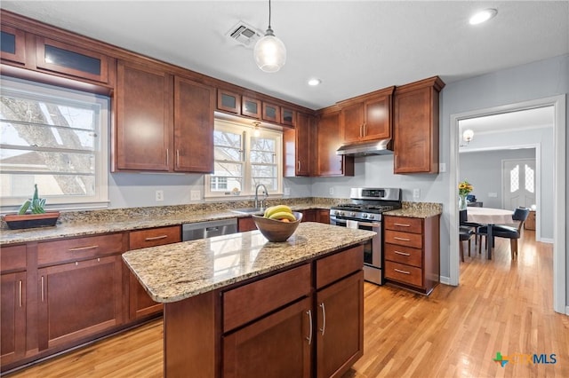 kitchen with under cabinet range hood, light wood-style flooring, visible vents, and appliances with stainless steel finishes