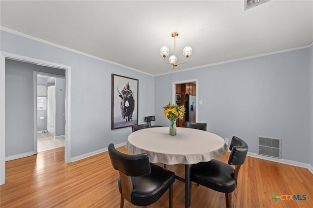 dining space with a chandelier, light wood-style flooring, visible vents, and baseboards