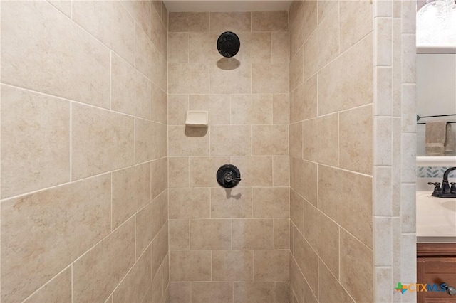 full bathroom featuring tiled shower and vanity